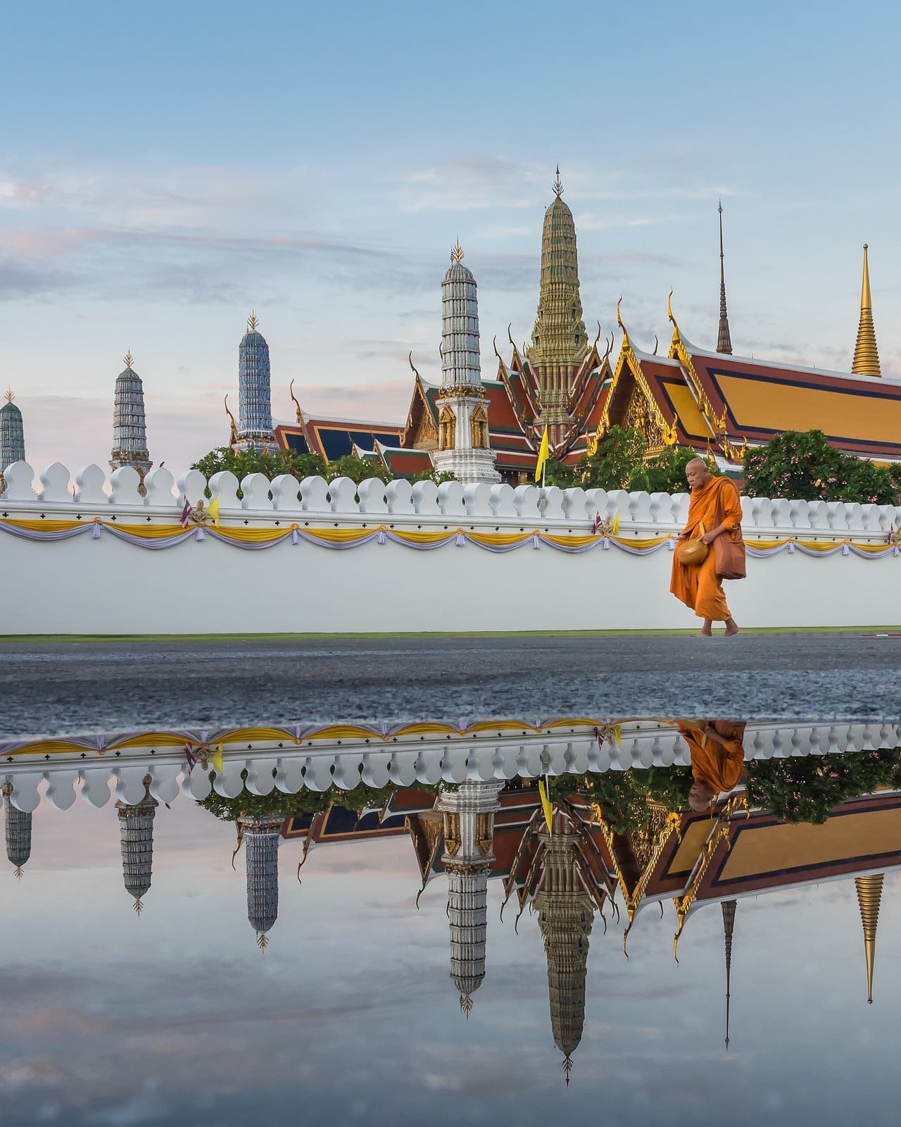 หลังฝนหยุด วัดพระแก้วทั้งวัดสะท้อนอยู่ในแอ่งน้ำหน้ากำแพง · 📷 Nawit science / Wikimedia Commons (CC BY-SA 4.0)